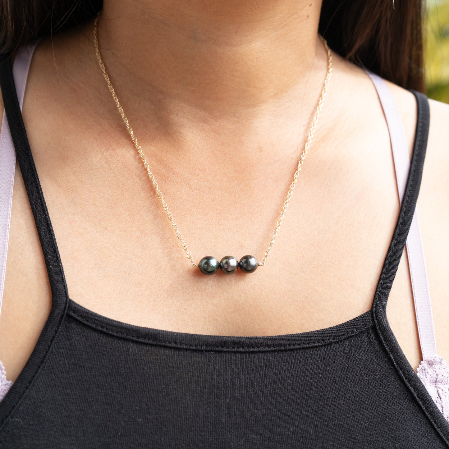 Necklace with three tahitian pearls worn by a person outdoors