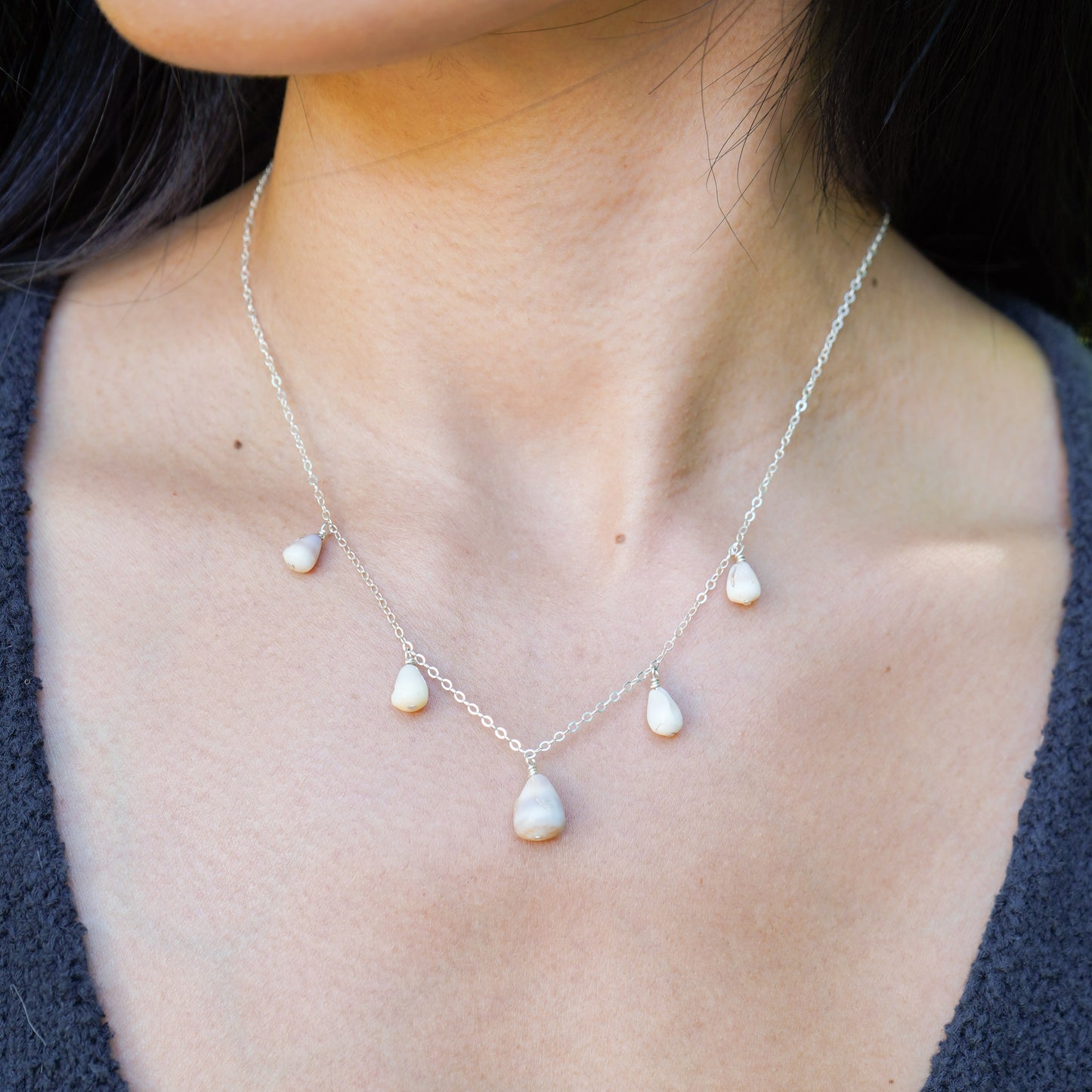 Tiny cone shell necklace on a person with a blurred background