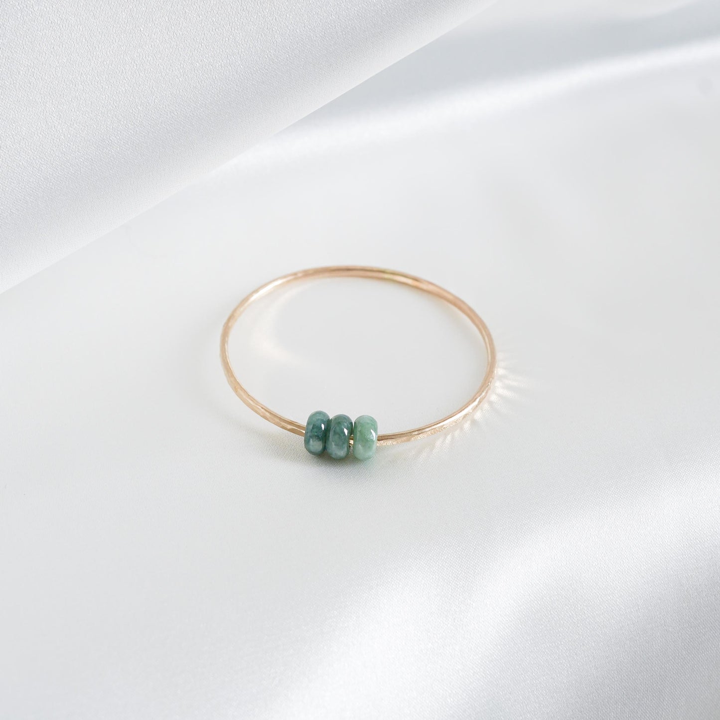 Gold bracelet with green jade beads on a white background