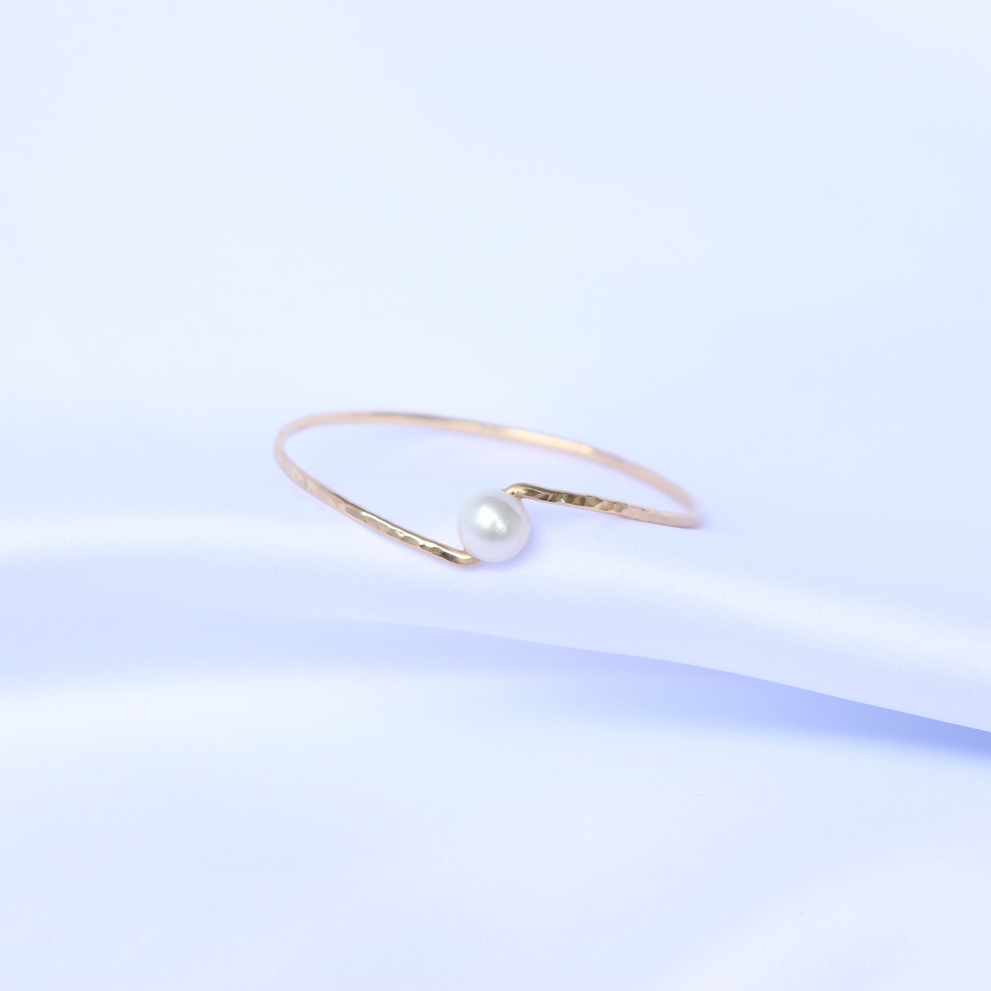 Gold bracelet with a white pearl on a white background