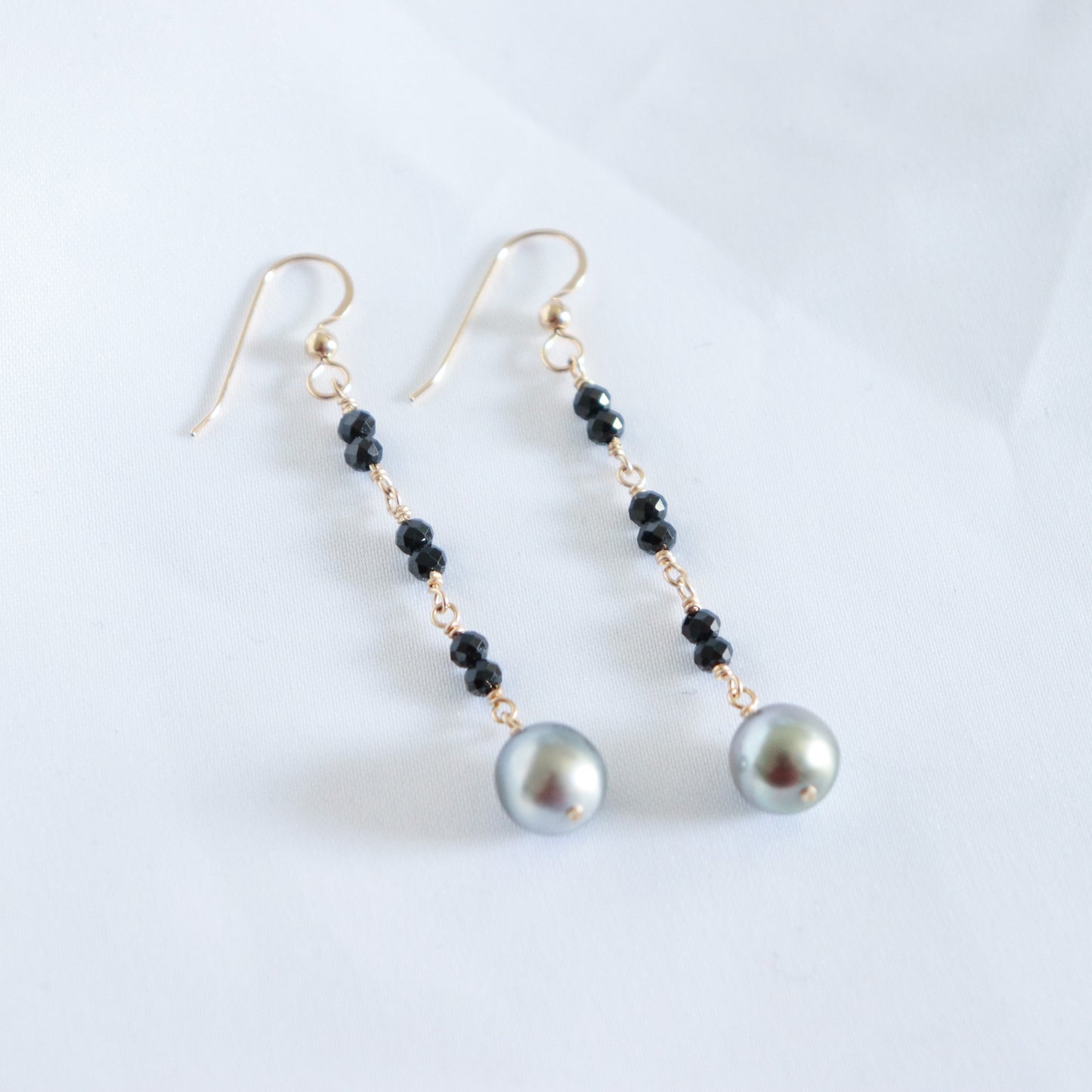 Pair of pearl earrings with black beads on a white background