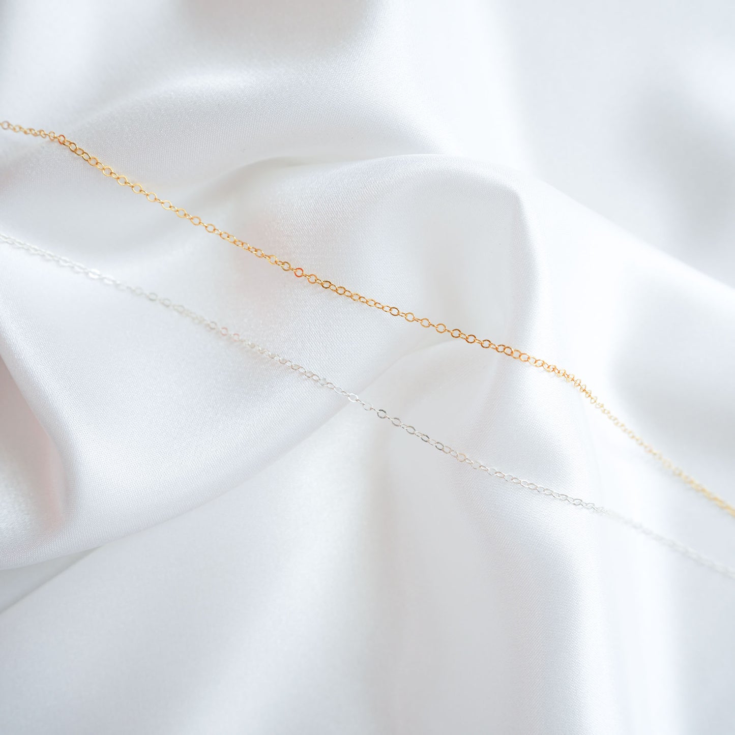 Gold and silver chain on a white fabric background