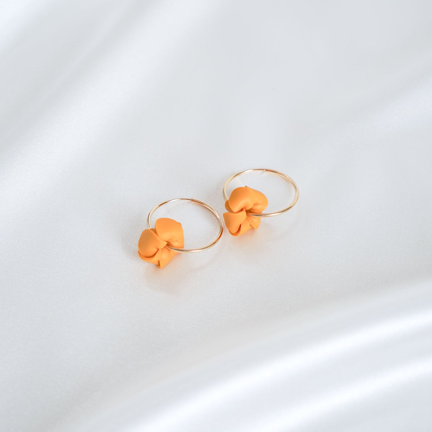 Pair of orange flower-shaped earrings on a white background