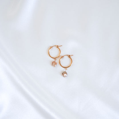 Gold hoop earrings with pearl drops on a white background