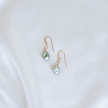 Pair of gold earrings with green pearls on a white background