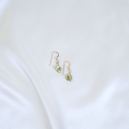 Pair of gold earrings with green pearls on a white background