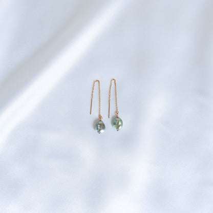 Pair of gold chain earrings with blue keshi pearls against a white background