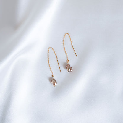 Pair of gold earrings with small brown keshi beads on a white background