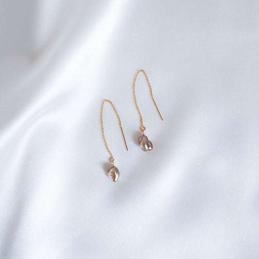 Pair of gold earrings with small brown keshi beads on a white background