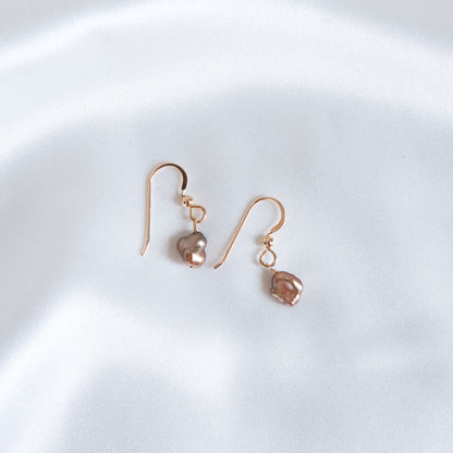 Pair of gold earrings with brown pearls on a white background