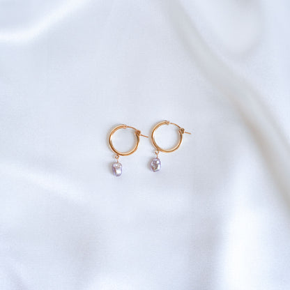 Gold hoop earrings with pearl drops on a white background