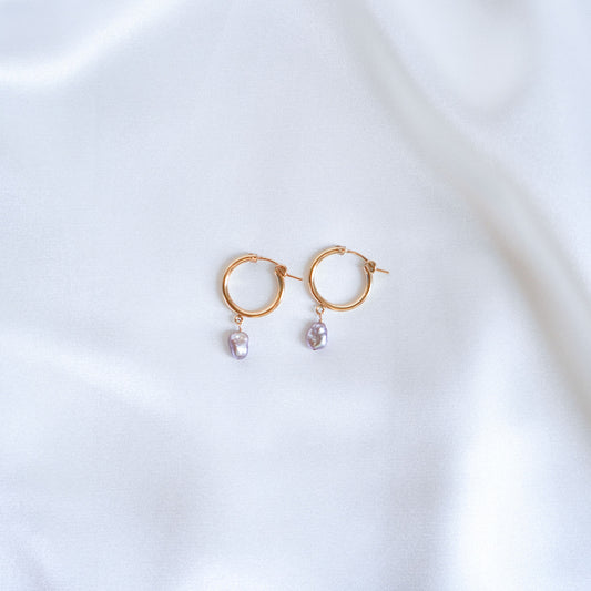 Gold hoop earrings with pearl drops on a white background