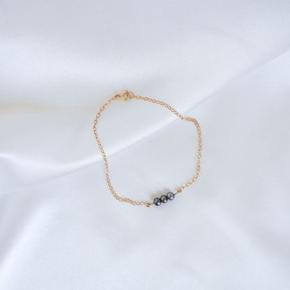 Gold bracelet with three tahitian keshi pearls on a white background
