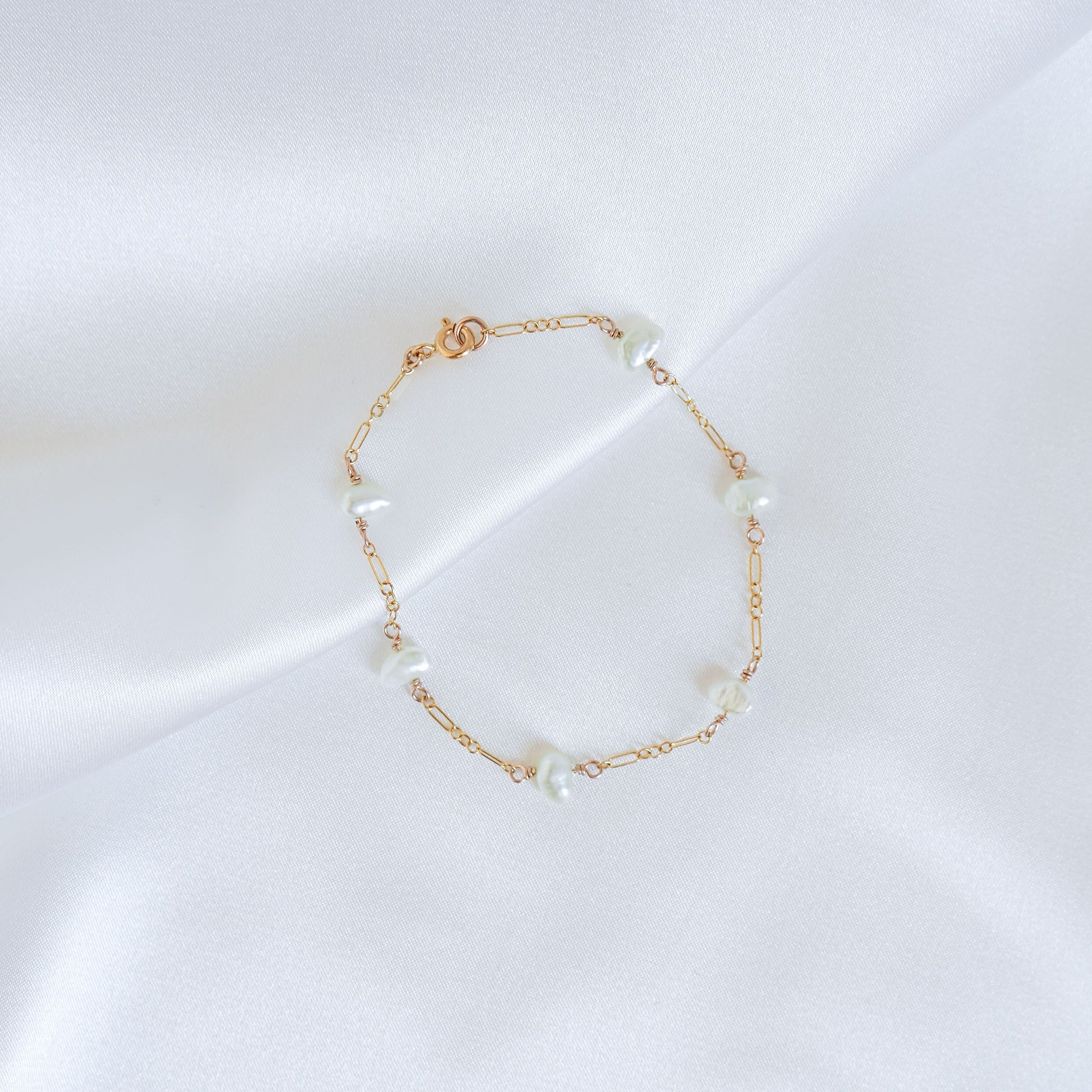 Gold bracelet with pearls on a white background