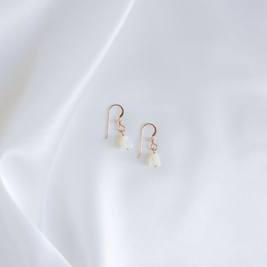 Pair of gold earrings with white pikake flower beads on a white background