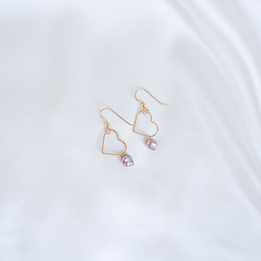 Gold heart-shaped earrings with pink keshi pearls on a white background