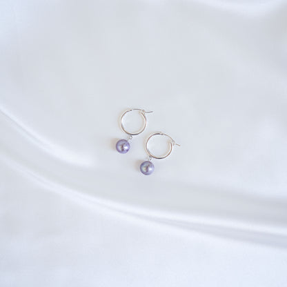Pair of silver hoop earrings with edison pearls on a white background