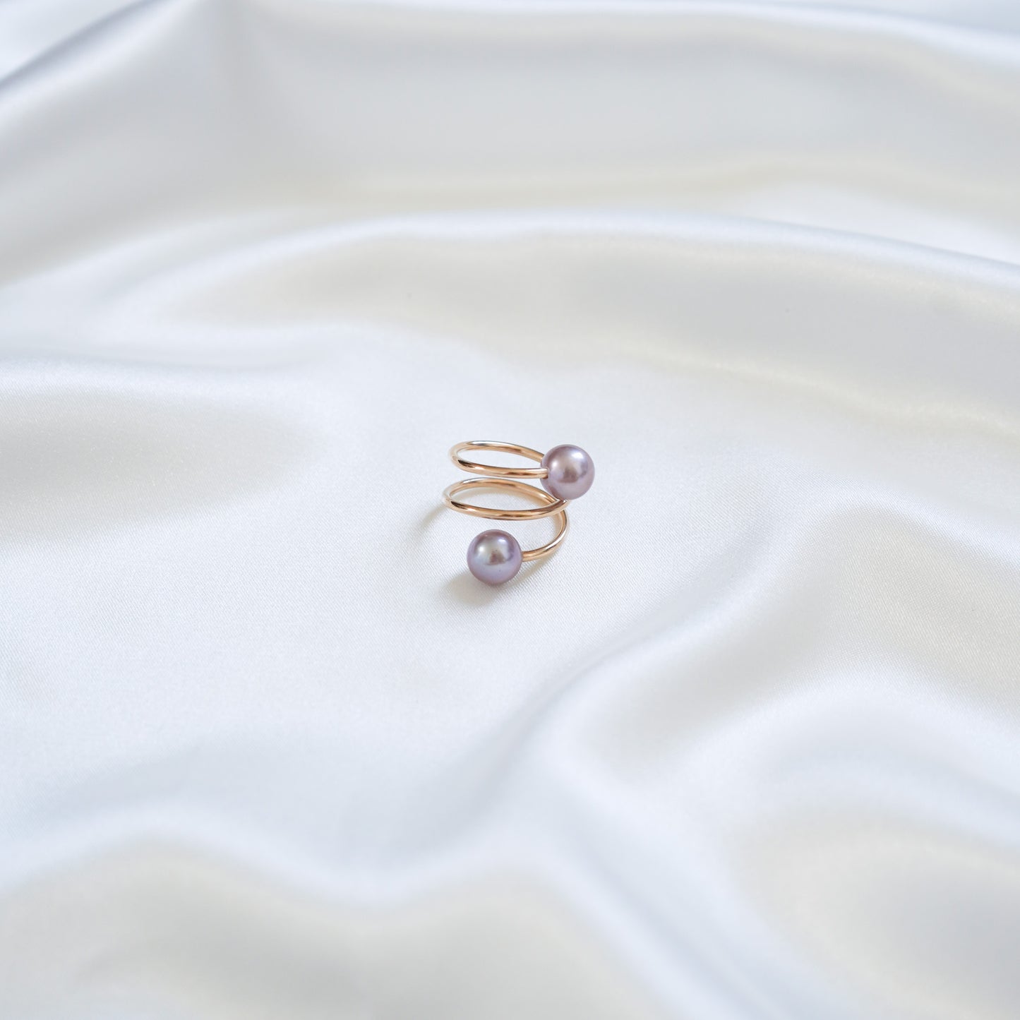 Gold ring with pink pearls on a white fabric background
