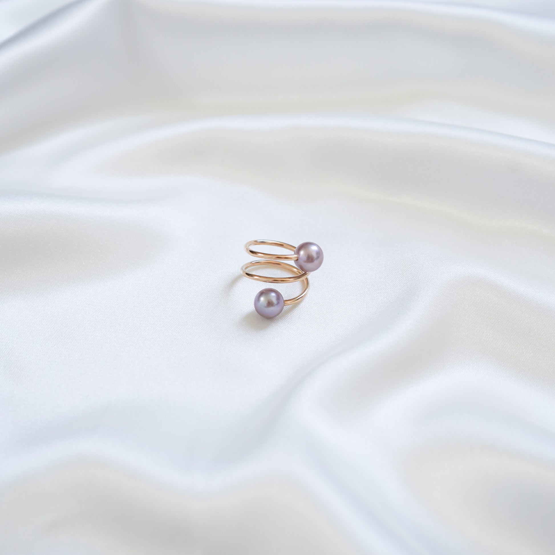 Gold ring with pink pearls on a white fabric background