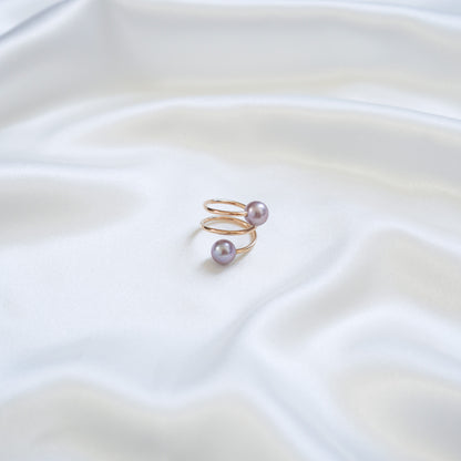 Gold ring with pink pearls on a white fabric background