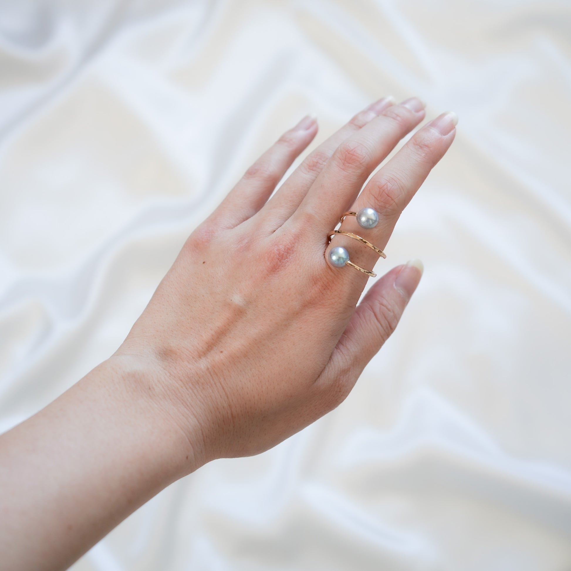 Hand wearing a pearl ring on a white background