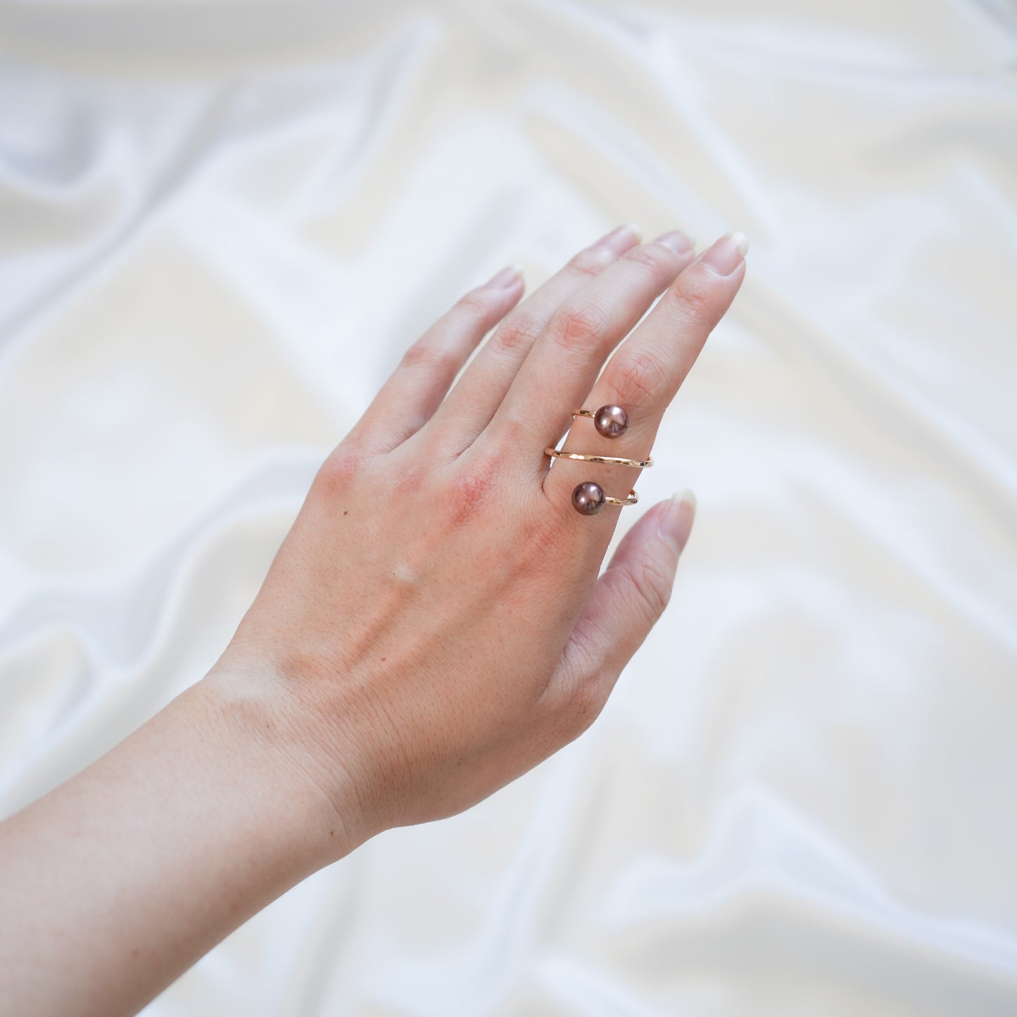 Hand wearing a pearl ring on a white background