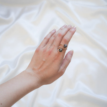 Hand wearing a pearl ring on a white background