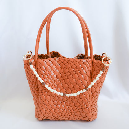 Brown woven handbag with white beaded bag lei on a white background