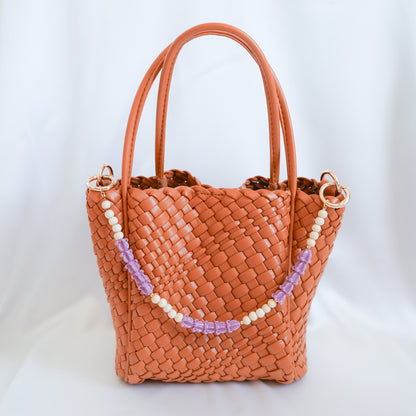 Woven handbag with beaded bag lei strap on a white background