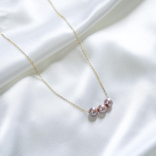 Pearl necklace with pink pearls on a white fabric background