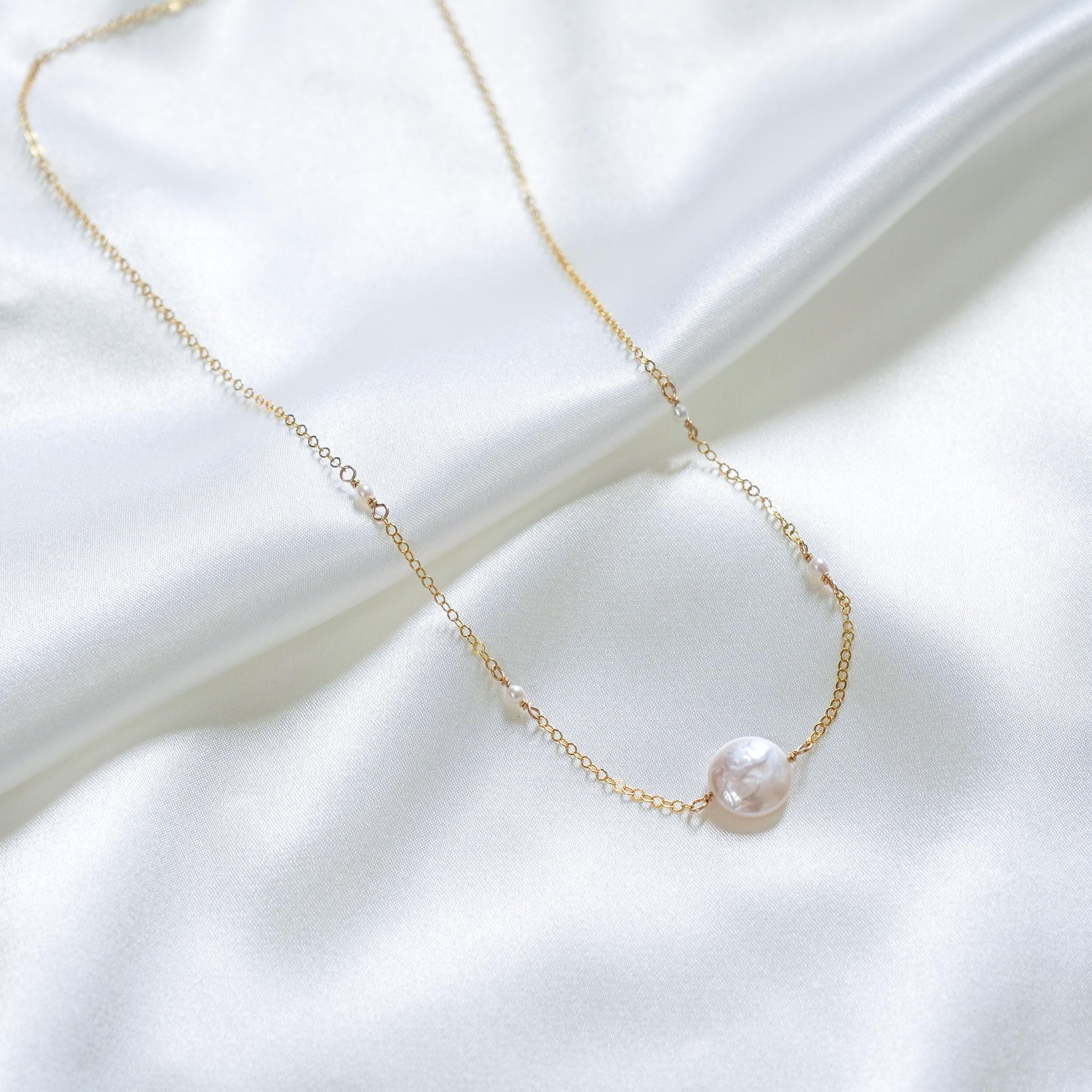 Gold necklace with large white pearl bead and smaller white pearls