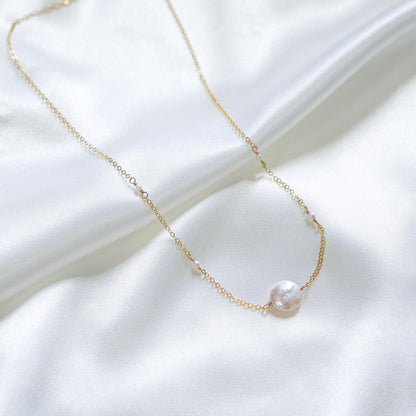 Gold necklace with large white pearl bead and smaller white pearls