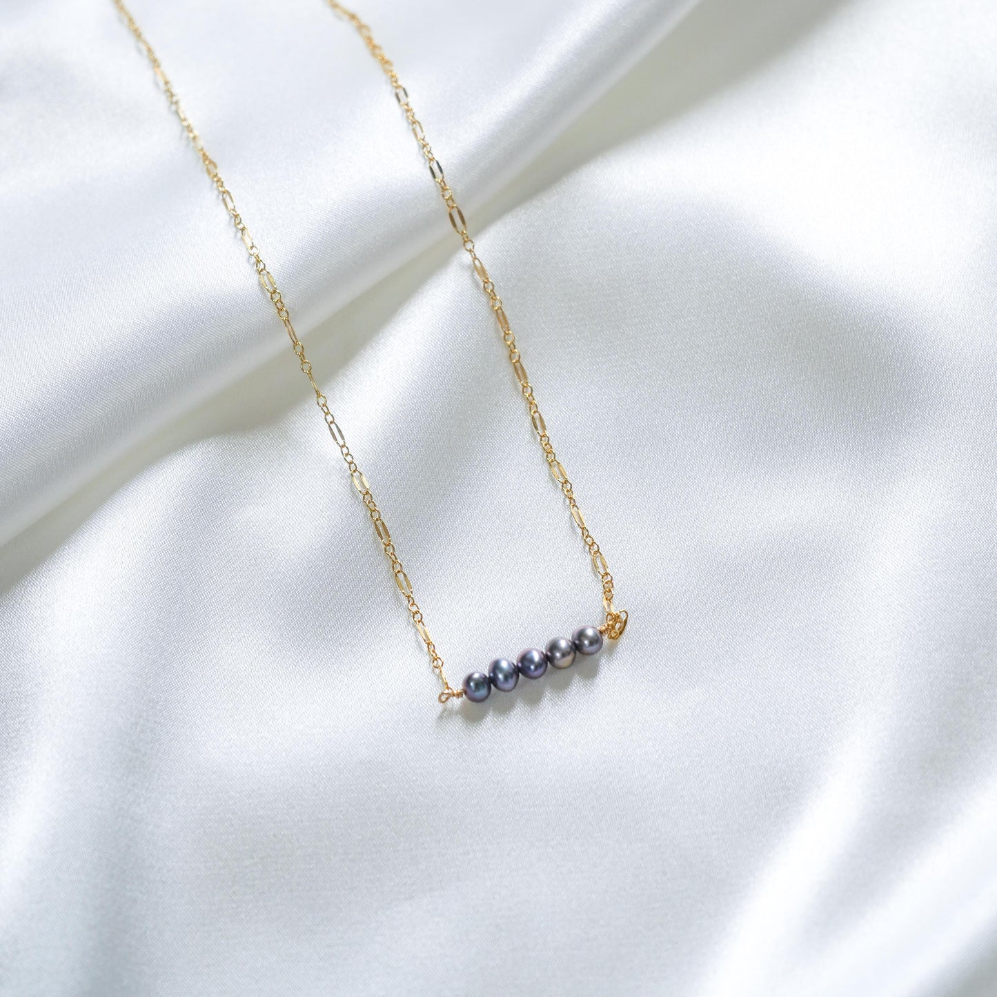 Gold necklace with blue pearls on a white fabric background