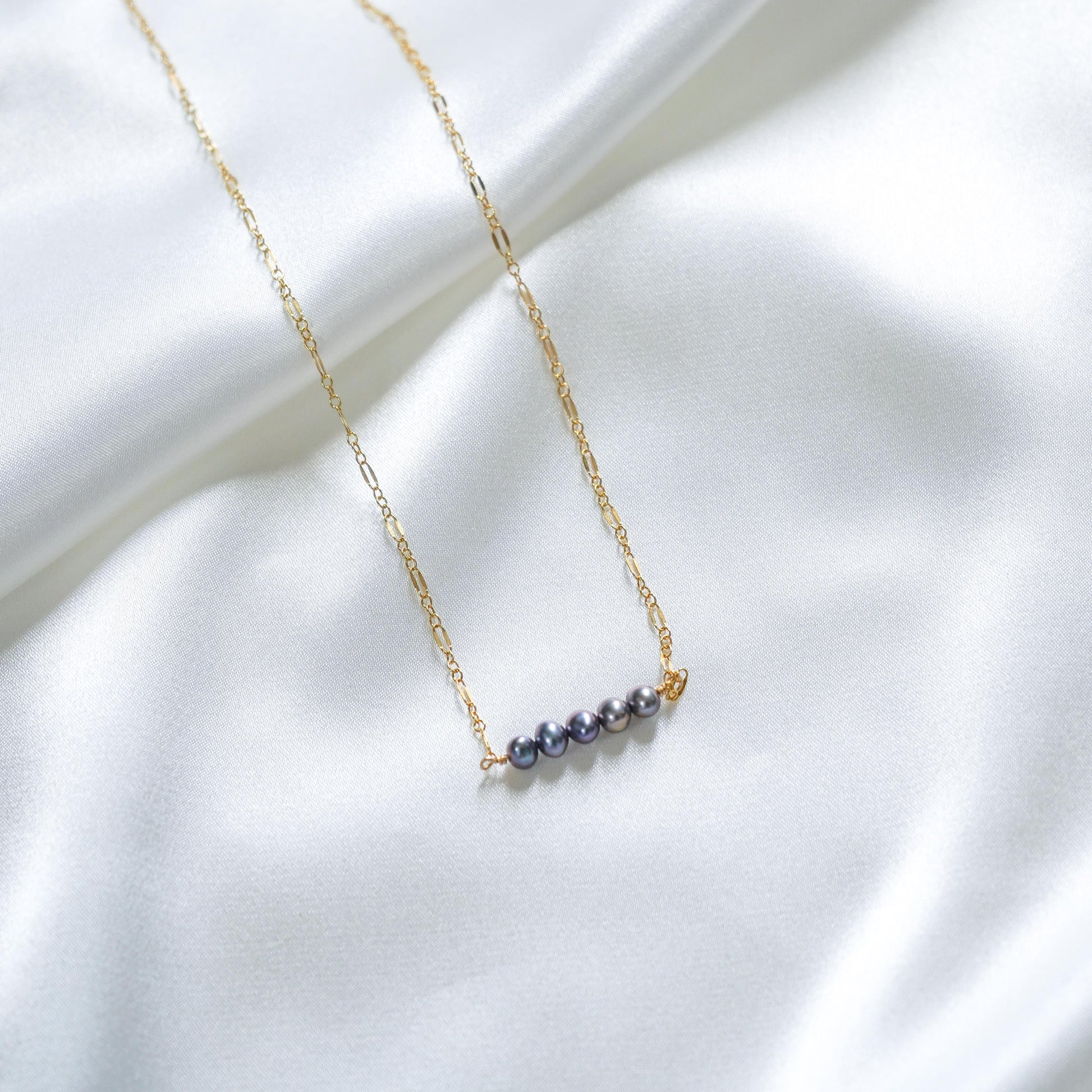 Gold necklace with blue pearls on a white fabric background