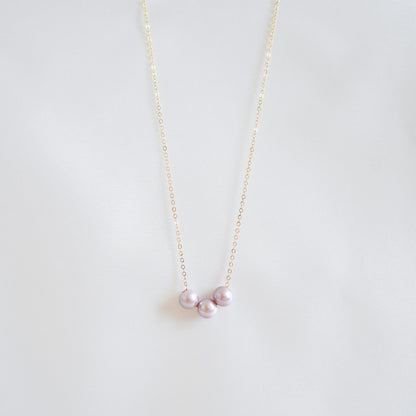 Pink pearl necklace on a thin chain against a light gray background