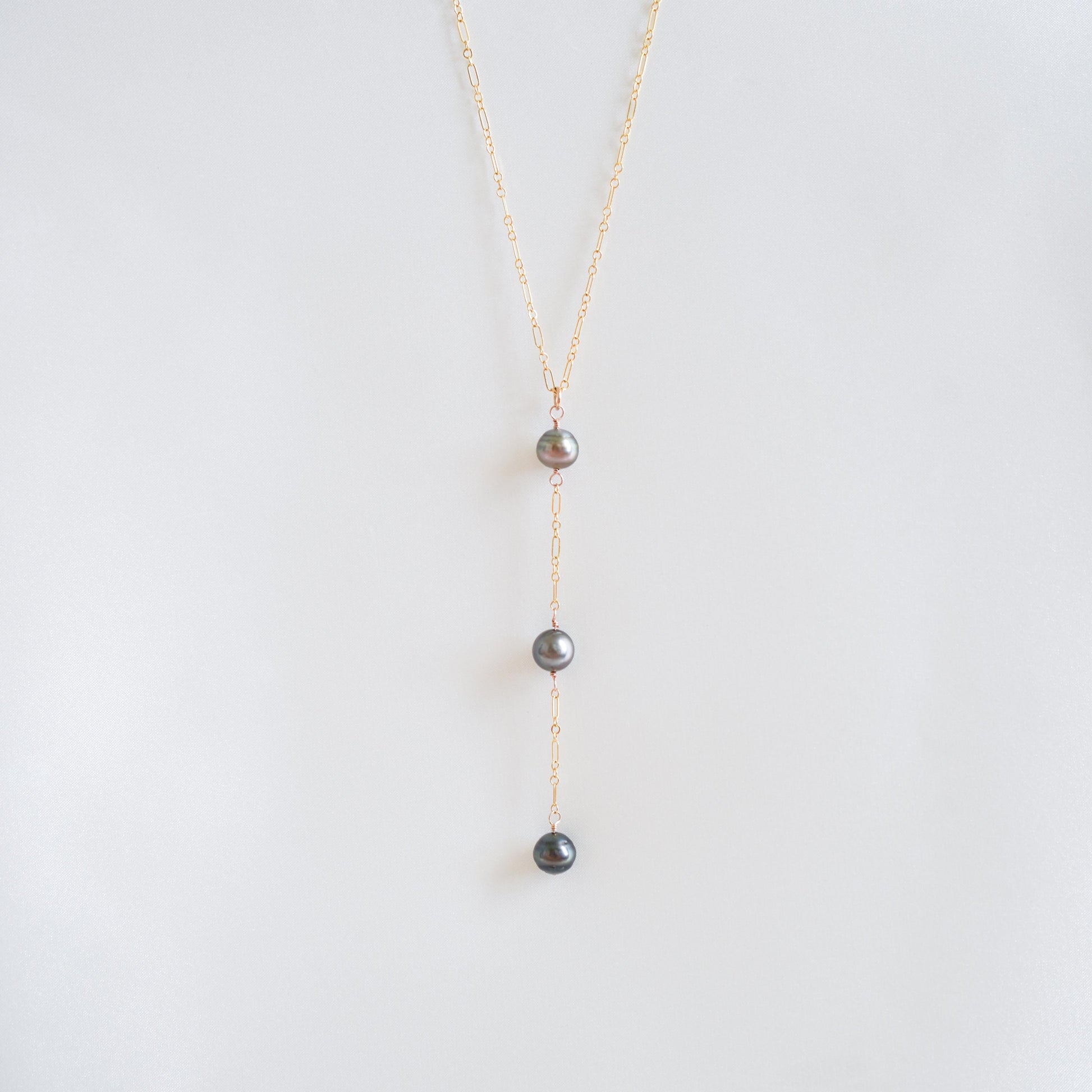 Pearl necklace on a thin gold chain against a white background