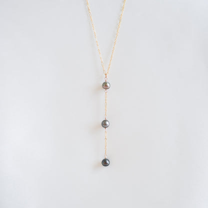 Pearl necklace on a thin gold chain against a white background