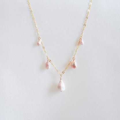 Necklace wit dangling pink pearls and white cone shell on gold chain