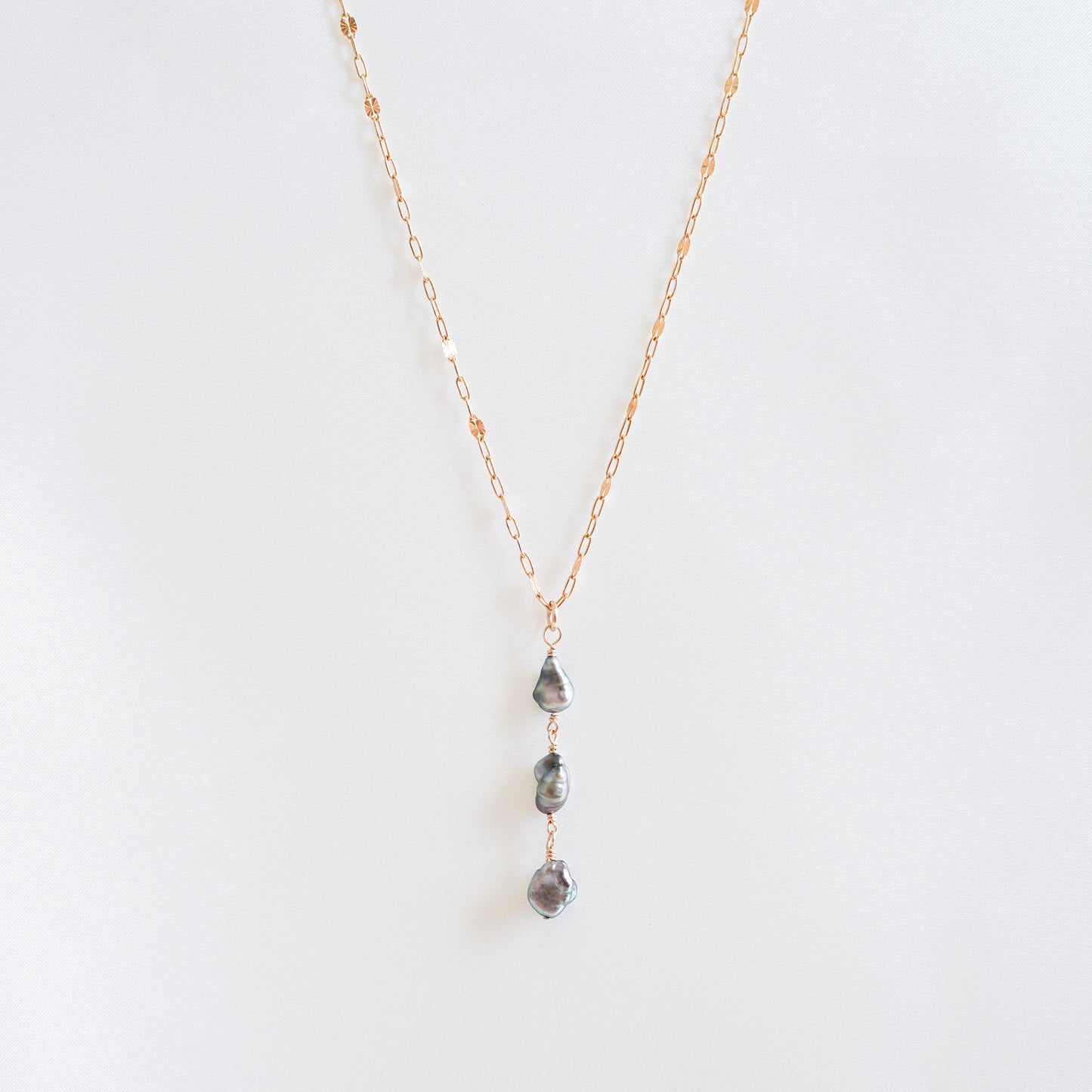 Necklace with three hanging keshi pearls on a white background