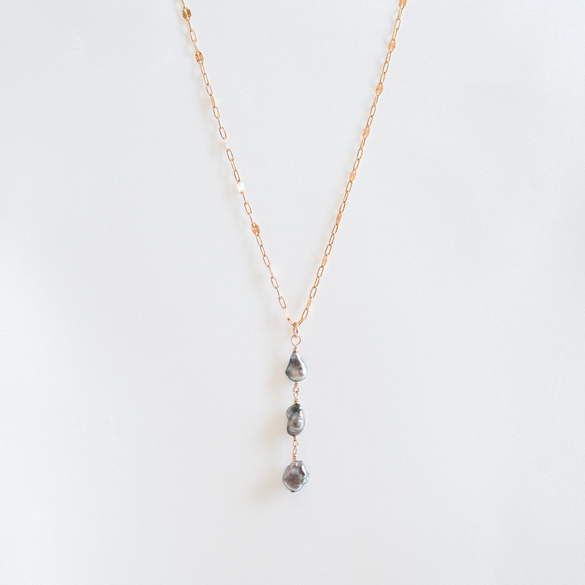 Necklace with three hanging keshi pearls on a white background