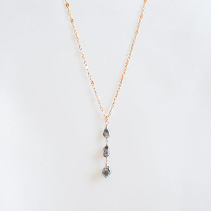 Necklace with three hanging keshi pearls on a white background