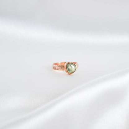 Gold ring with a green keshi pearl on a white background