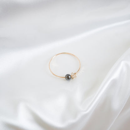 Gold bracelet with a single pearl and star charm on a white background