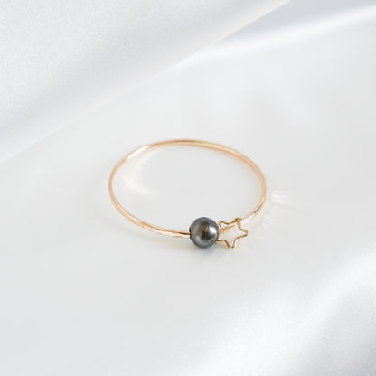 Gold bracelet with a single pearl and star charm on a white background