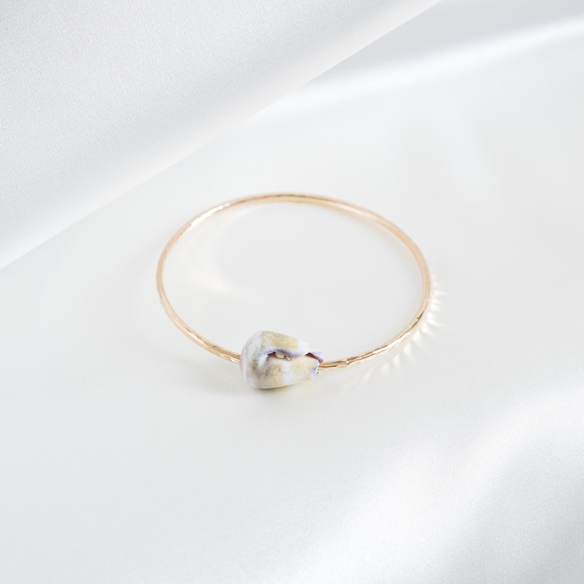 Gold bracelet with a shell on a white background