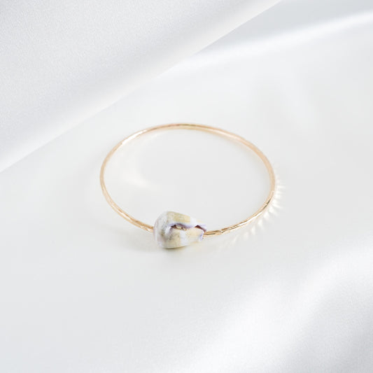 Gold bracelet with a shell on a white background