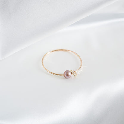 Gold bracelet with a single pearl and heart charm on a white background