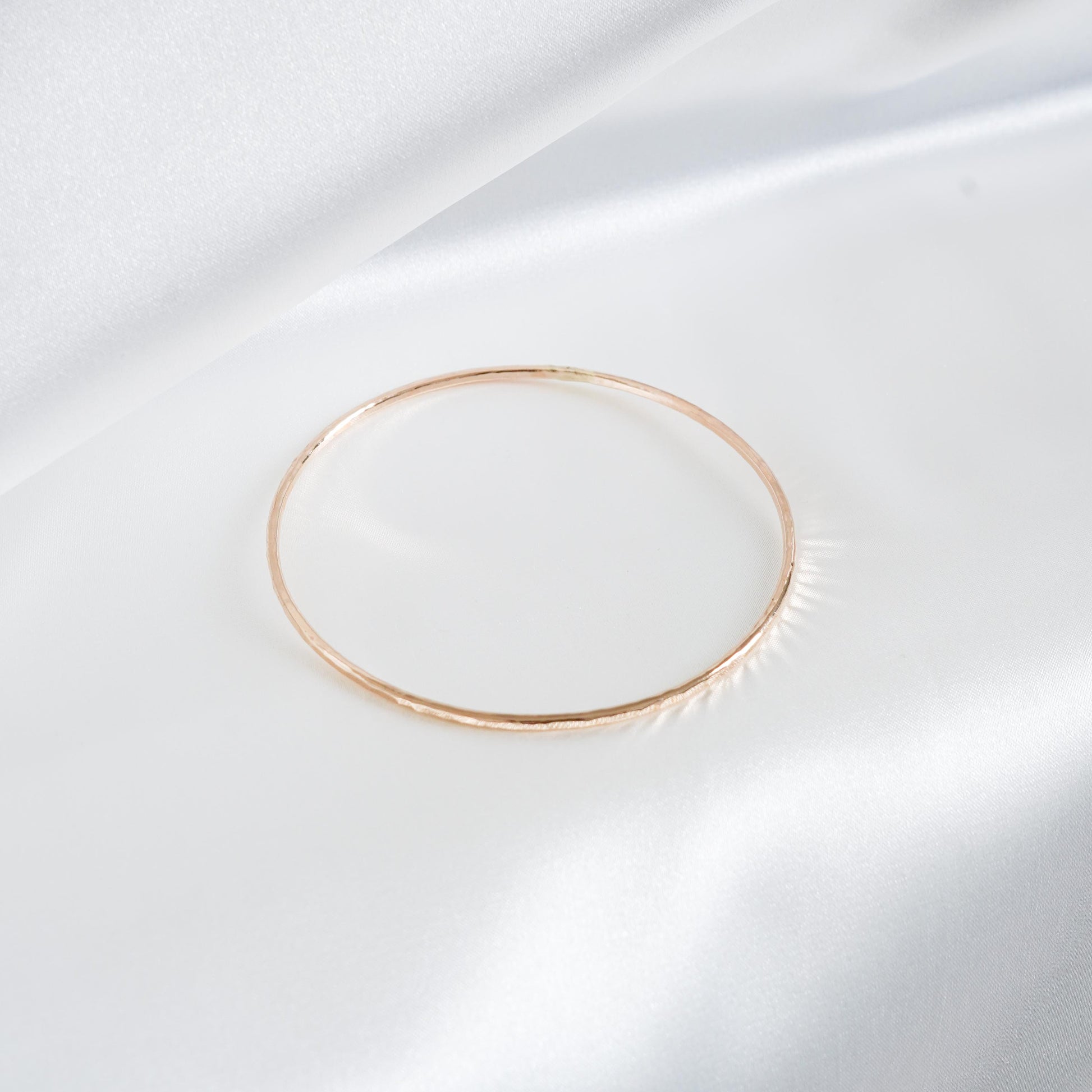 Gold simple bracelet on white satin background