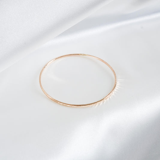 Gold simple bracelet on white satin background