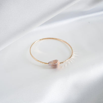 Gold bracelet with a pink white shell on a white background